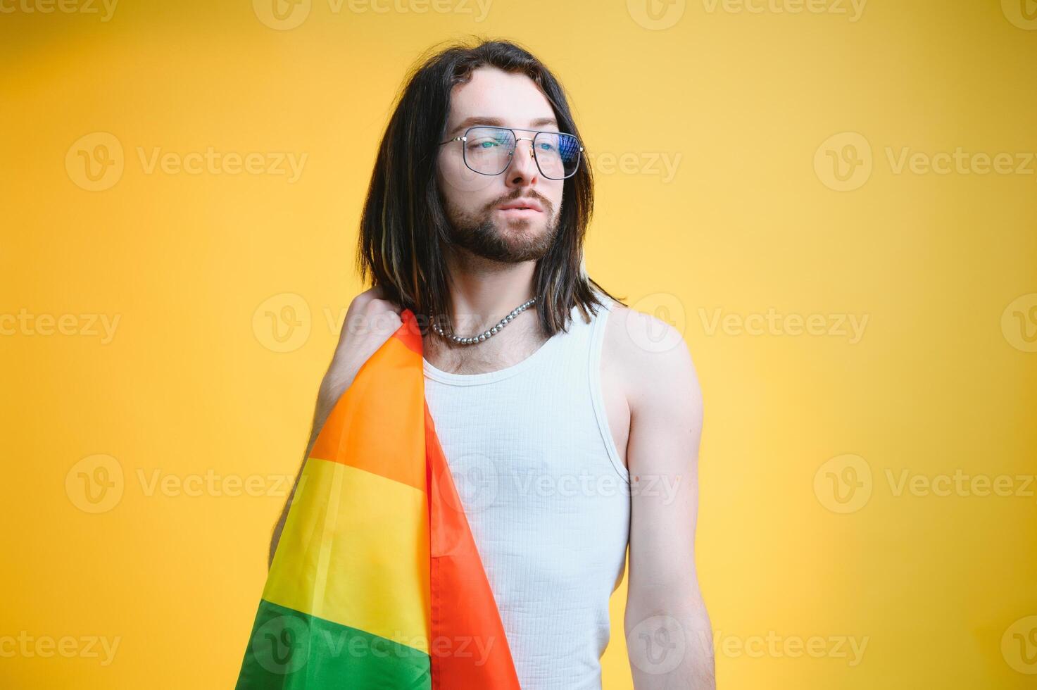 gay uomo con un' gay orgoglio bandiera sorridente e guardare lontano su giallo sfondo foto