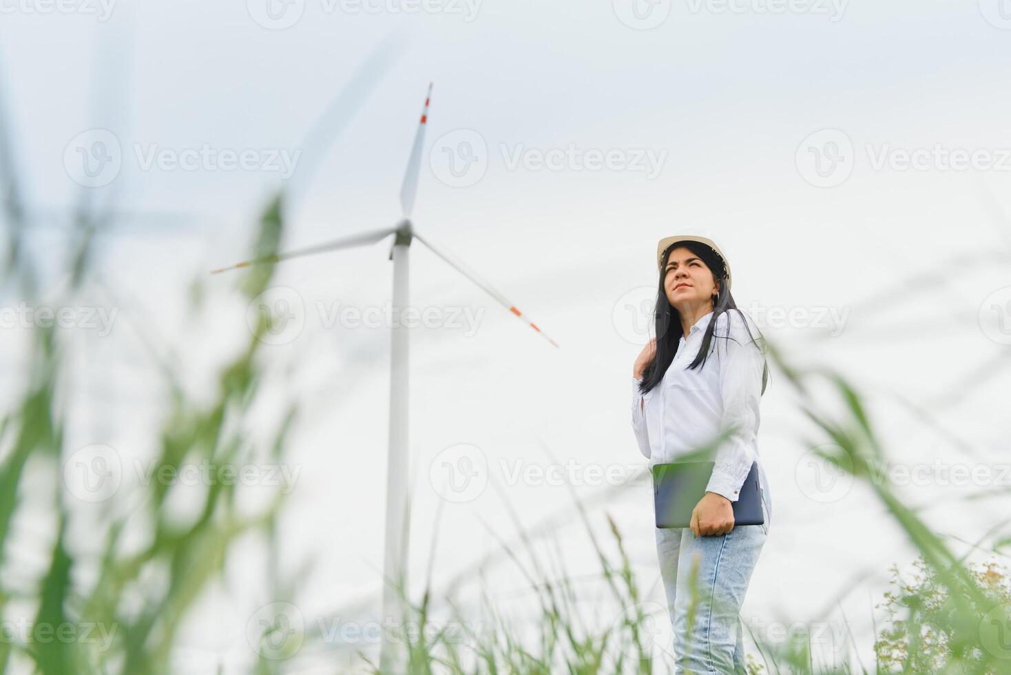 ingegnere delle donne che lavora e tiene il rapporto alla stazione del generatore di energia dell'azienda agricola della turbina eolica sulla montagna, gente della Tailandia foto