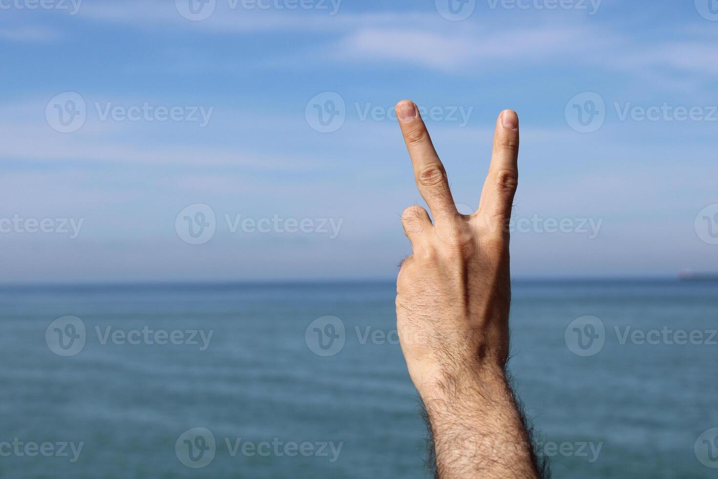 mano fare, mostrare numero Due gesto simbolo su blu estate cielo natura sfondo. Esprimere a gesti numero 2. numero Due nel cartello linguaggio. foto