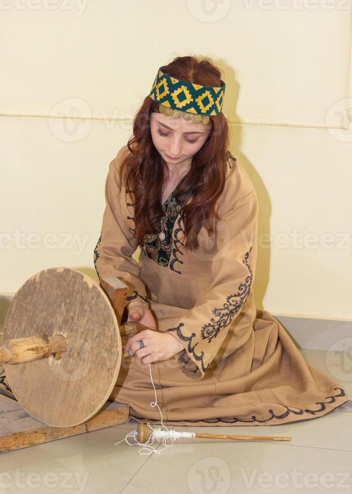 armeno giovane donna nel tradizionale Abiti Lavorando nel casa foto
