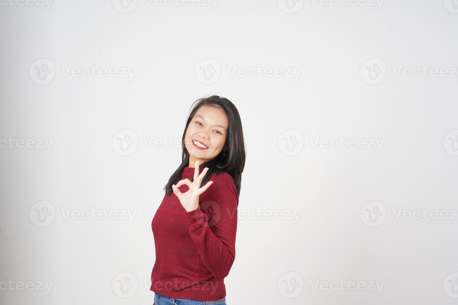 giovane asiatico donna nel rosso maglietta sorridente e mostrando va bene cartello isolato su bianca sfondo foto