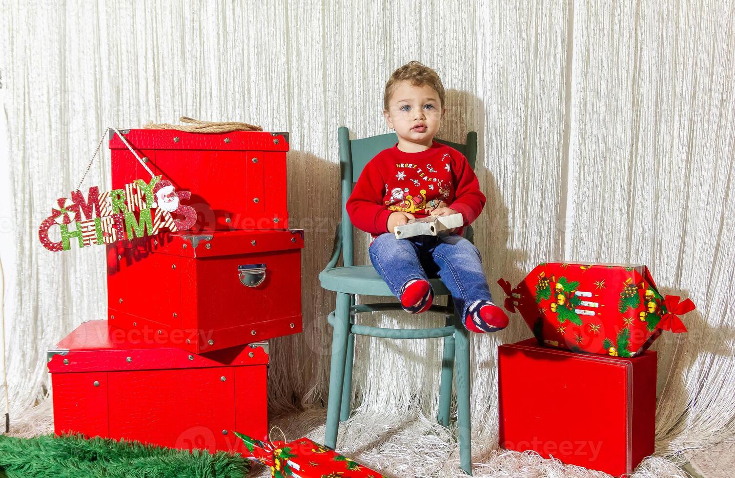 il poco bambino giocando con Natale decorazioni nel studio, poco bambino con Natale palla foto