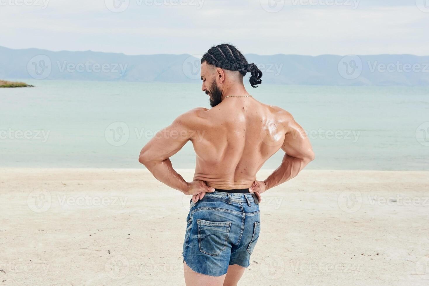 giovane muscolare uomo esercizio su il spiaggia, giovane muscolare uomo fare bodybuilding esercizi su il spiaggia, atletico giovane uomo su il spiaggia foto