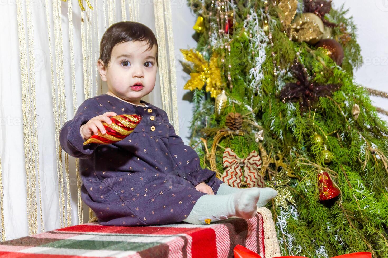 il poco bambino giocando con Natale decorazioni nel studio, poco bambino con Natale palla foto