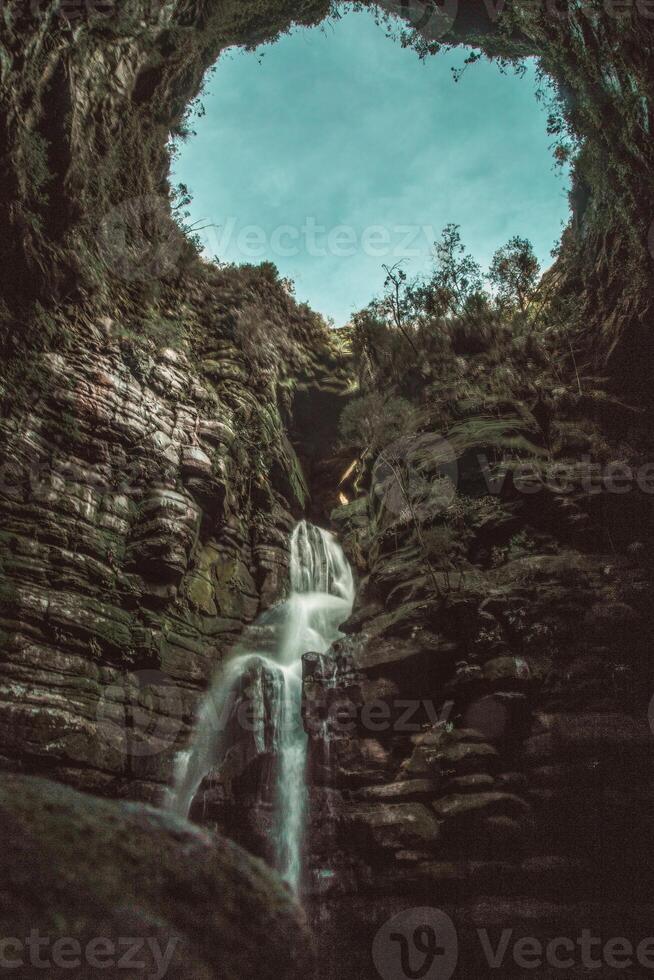 cascata nel il foresta con blu cielo e bianca nuvole - Vintage ▾ filtro foto