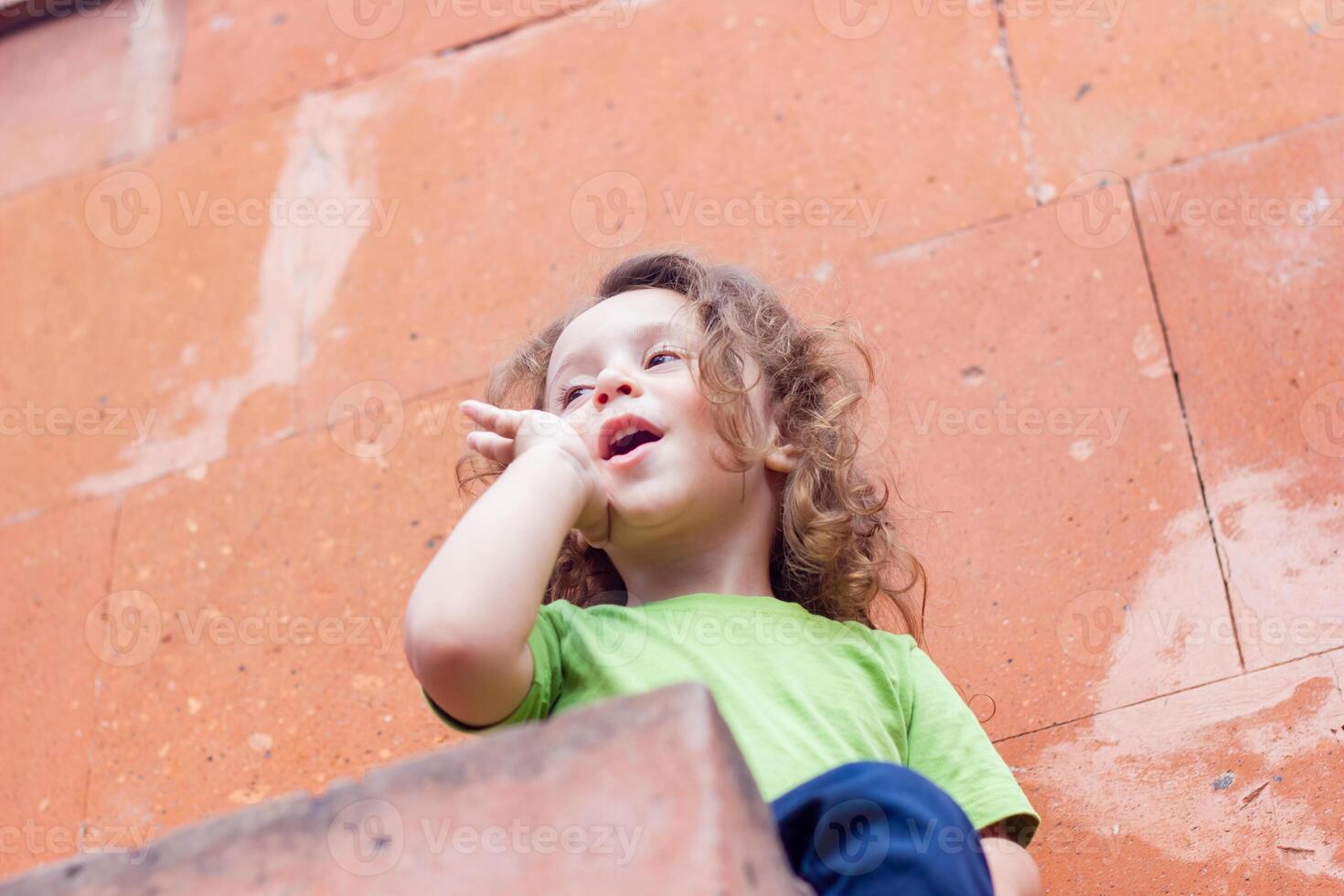 contento poco ragazzo giocando nel il parco, lungo capelli ragazzo nel il parco foto