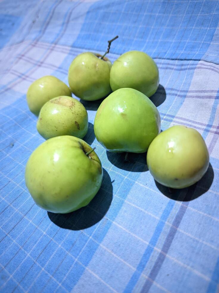 un' gruppo di verde mele seduta su un' blu e bianca scacchi tavolo stoffa foto