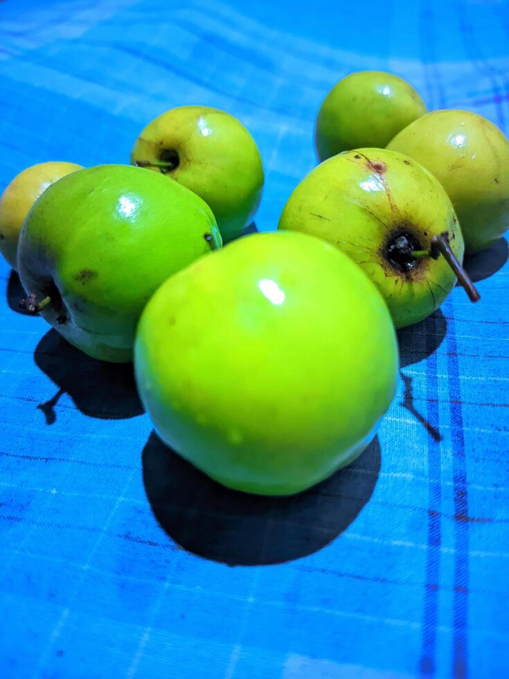 un' gruppo di verde mele seduta su un' blu e bianca scacchi tavolo stoffa foto