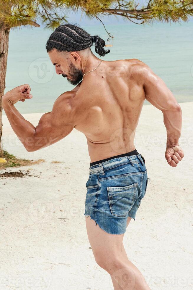 giovane muscolare uomo esercizio su il spiaggia, giovane muscolare uomo fare bodybuilding esercizi su il spiaggia, atletico giovane uomo su il spiaggia foto