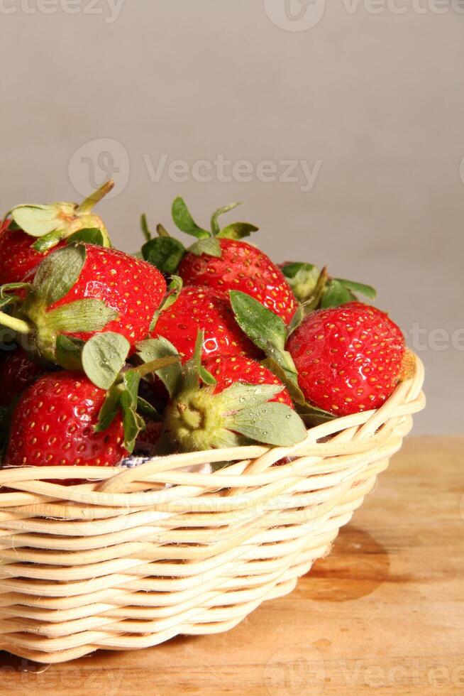 un' cestino di fragole su un' di legno tagliare tavola su bianca sfondo foto