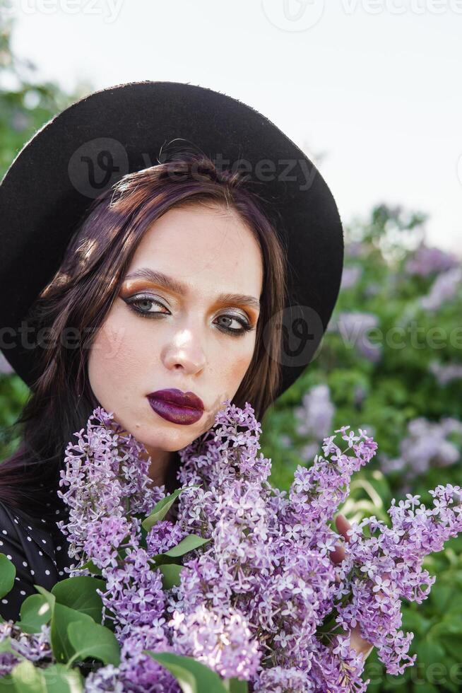 un' alla moda ragazza con buio capelli, un' primavera ritratto nel lilla toni nel estate. luminosa professionale trucco. foto