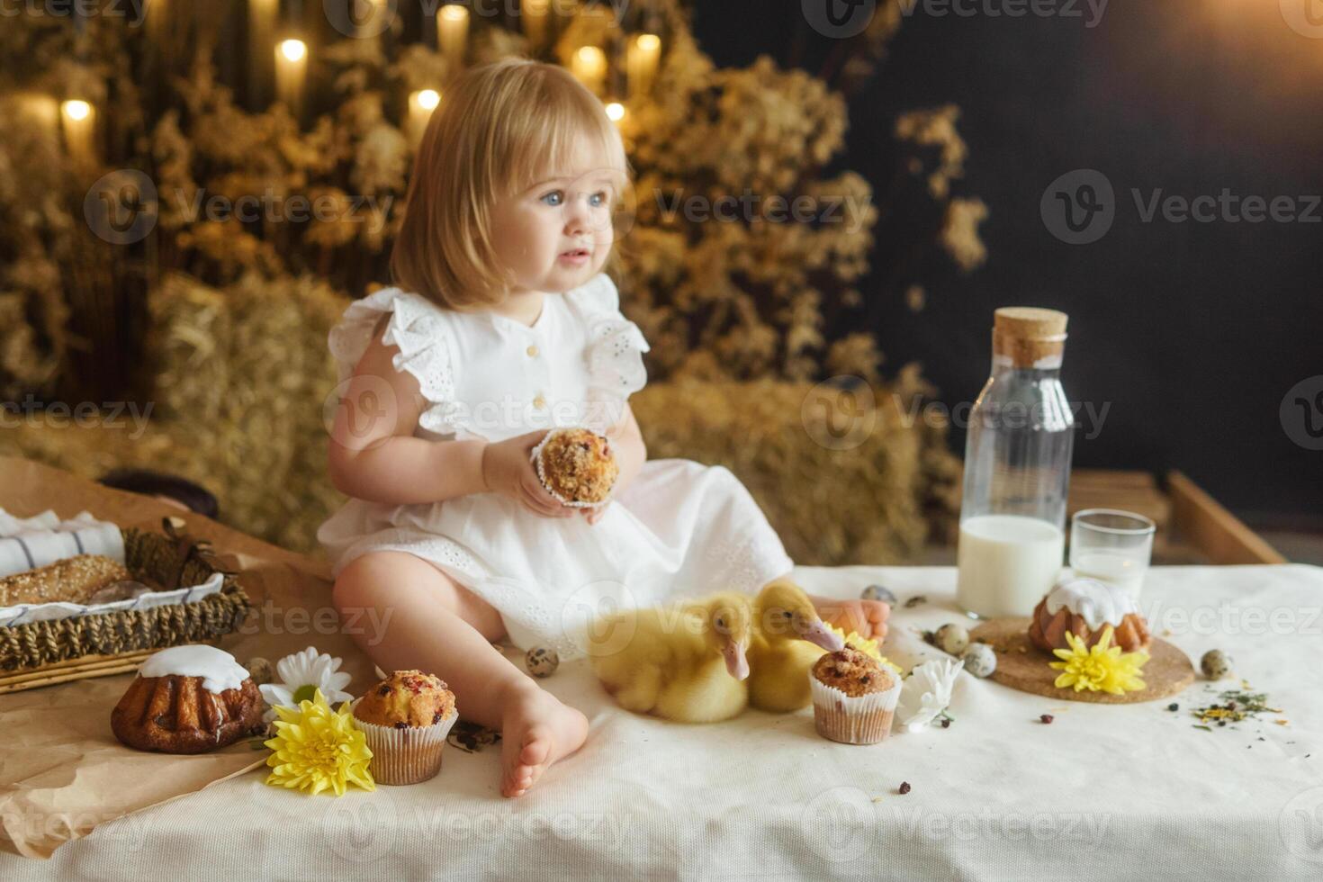 un' poco ragazza è seduta su il Pasqua tavolo e giocando con carino soffice anatroccoli. il concetto di festeggiare contento Pasqua. foto