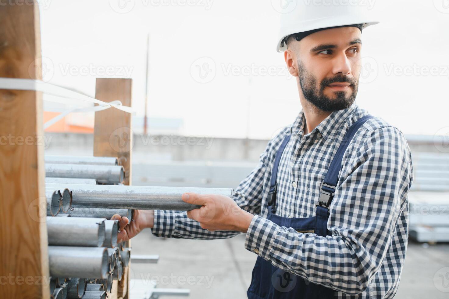 un' lavoratore detiene metallo tubi nel un' fabbrica magazzino. metallo rotolamento foto