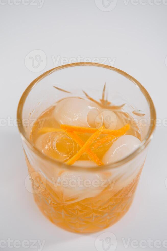 bicchiere di viale cocktail con grande ghiaccio cubo e arancia scorza, classico cocktail alcolizzato viale con arancia e vermut isolato su bianca sfondo foto