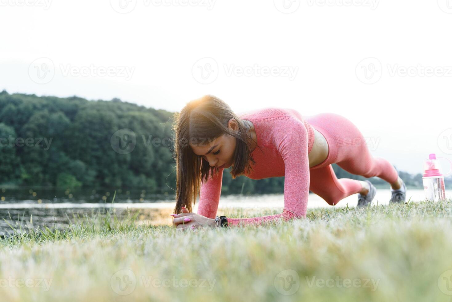 giovane caucasico donna fare attivo formazione esercizio su un' yoga stuoia vicino il fiume nel estate. concetto di salutare stile di vita foto