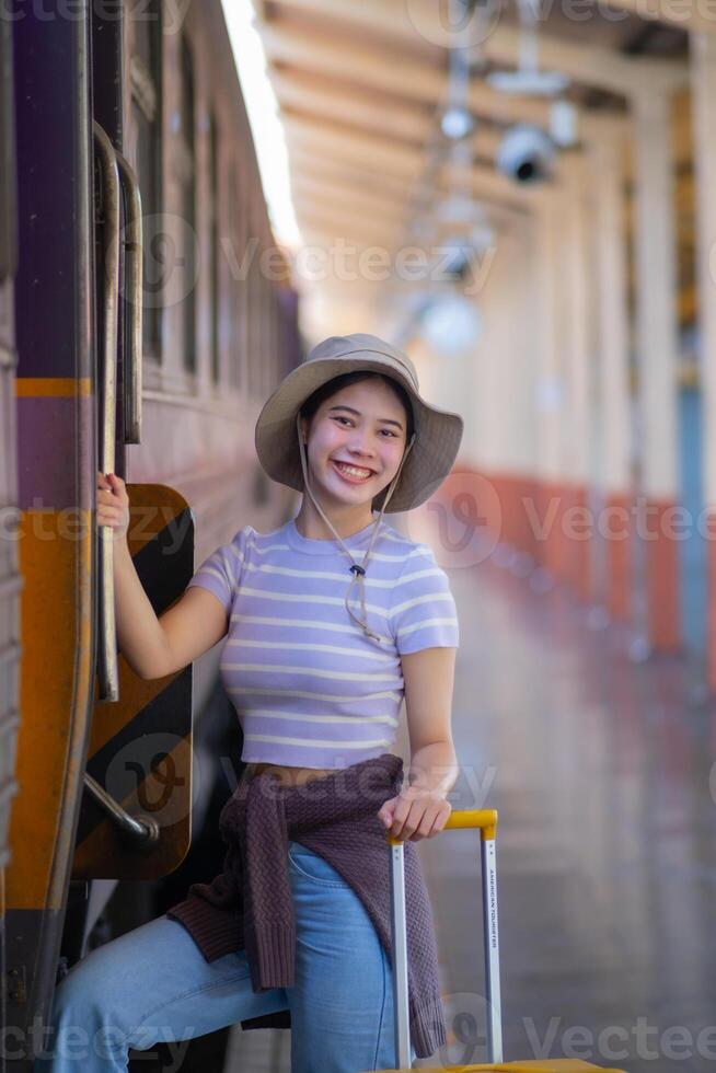 giovane donna con valigia aspetta a il la metropolitana stazione mentre il treno arriva, turismo e viaggio nel il estate. vacanze per il alunno. opera e viaggio foto