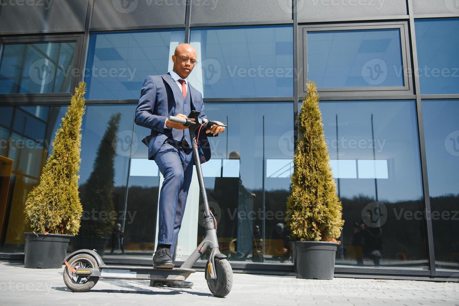 bello africano 30s uomo indossare cappotto sorridente mentre equitazione elettrico scooter all'aperto foto