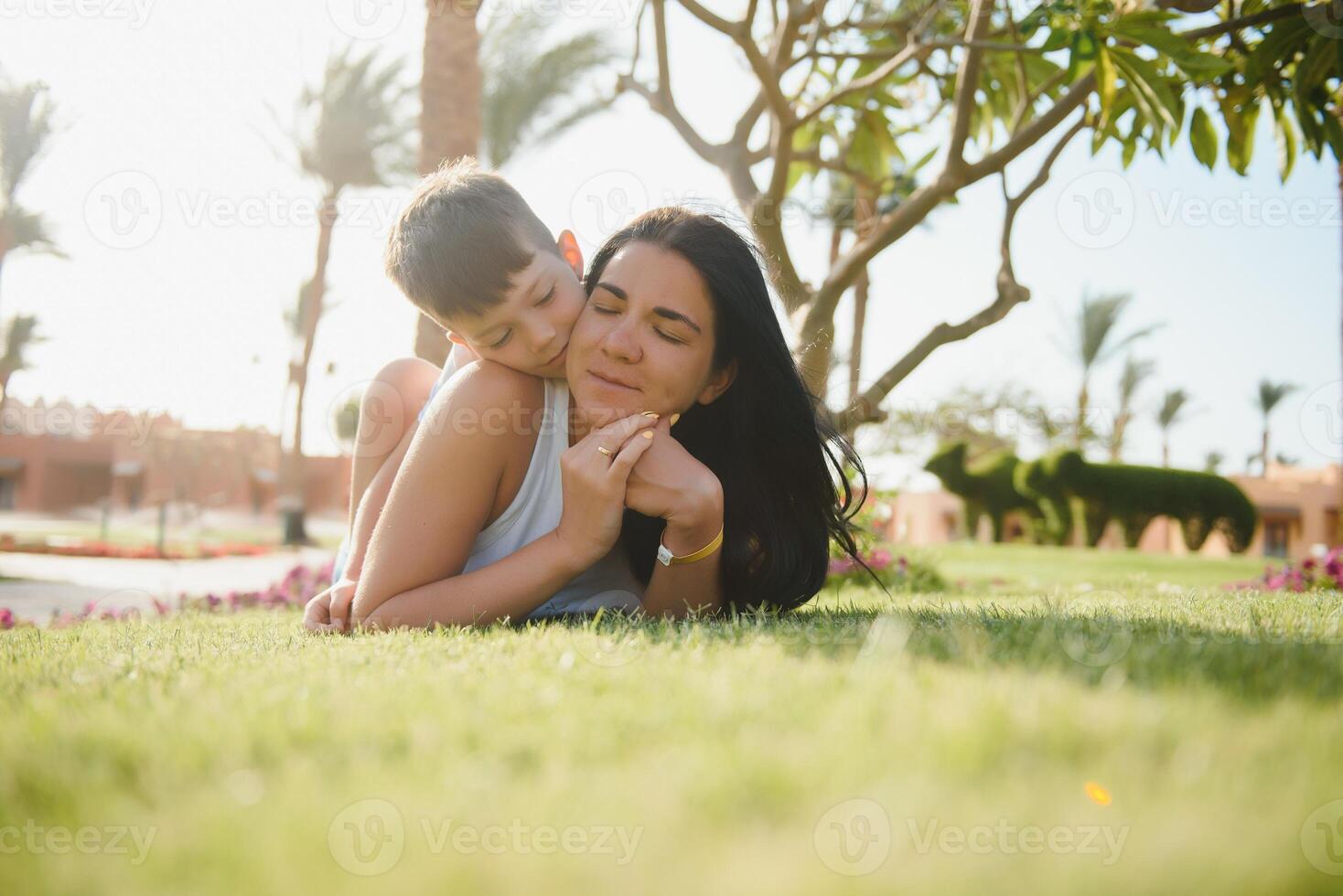 contento giovane madre con figlio dire bugie su erba foto