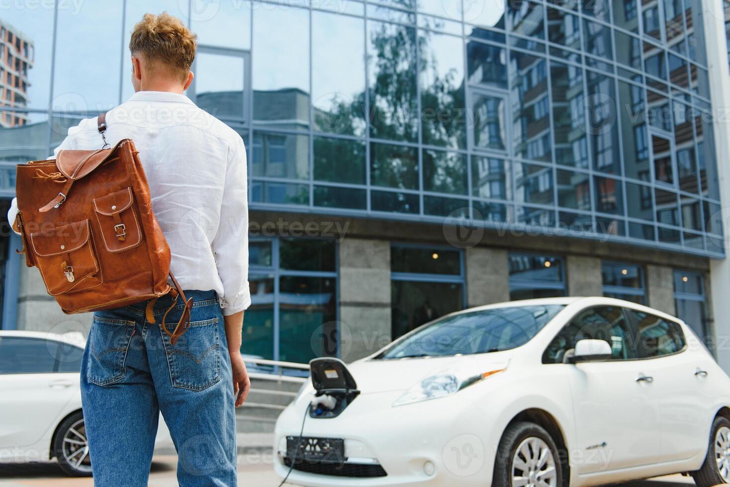 uomo con smartphone dopo finitura ricarica di batteria. maschio vicino elettrico veicolo foto