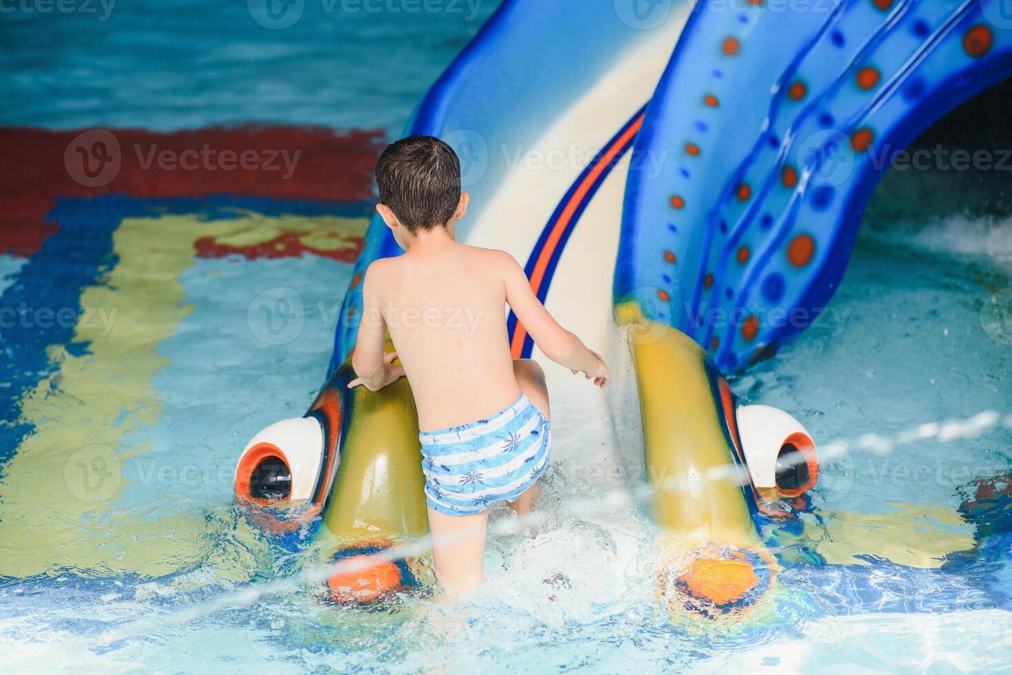 il ragazzo è rotolamento con un' acqua diapositiva a un' acqua parco nel poco roccia foto