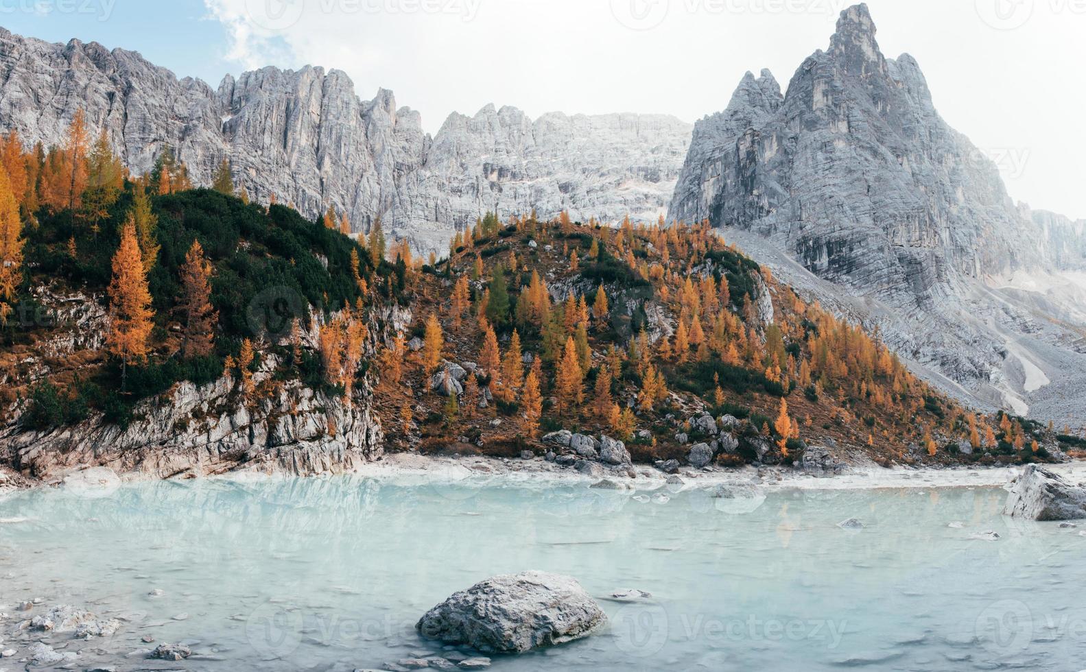 grandi colline e scogliere. giornata autunnale tra le maestose montagne. alberi di colore giallo sulle rocce. bellissimo lago di cristallo foto