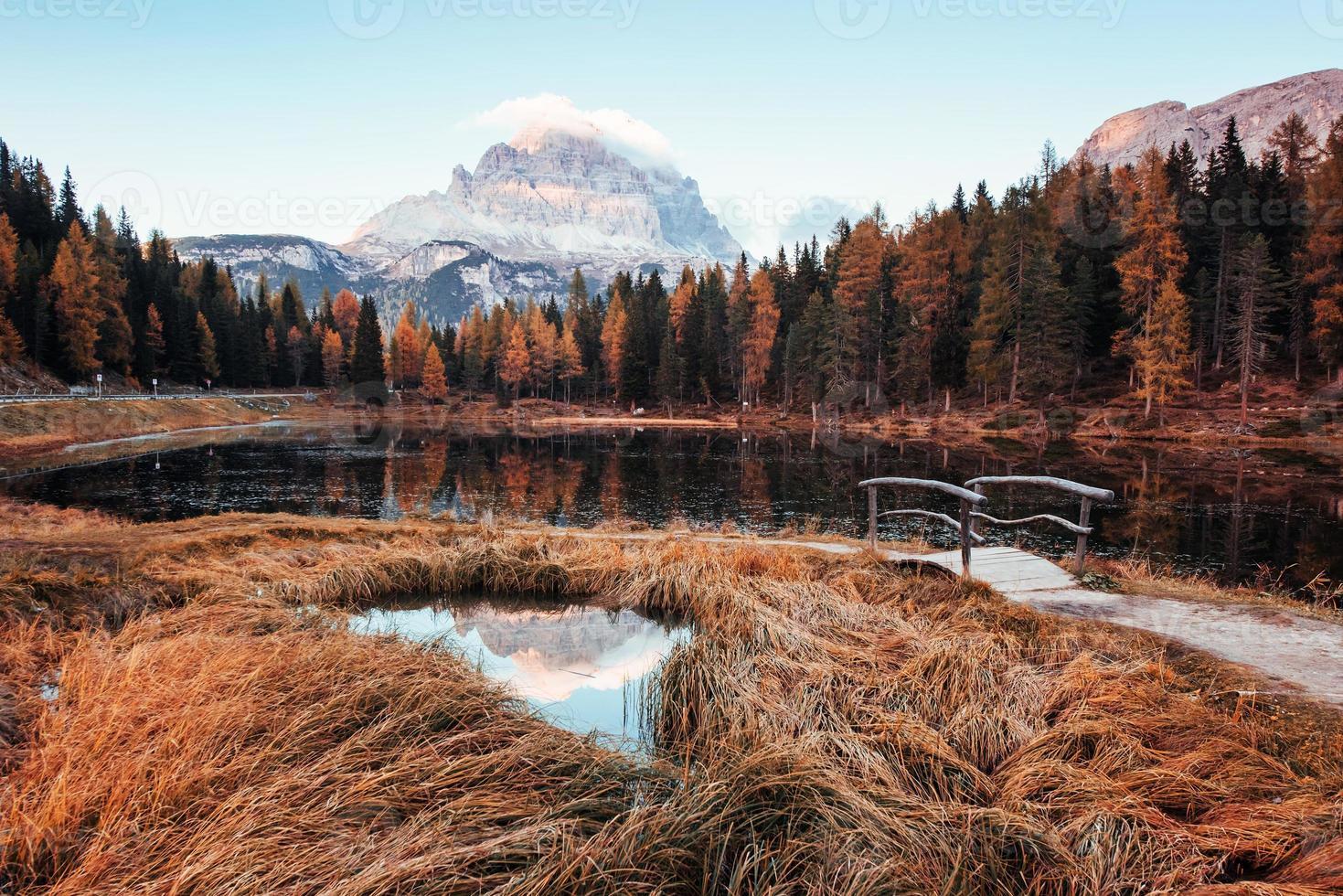 calma e bellezza. splendida vista delle maestose montagne con boschi di fronte a loro al giorno d'autunno. pozzanghera che va dal lago con ponticello al centro foto