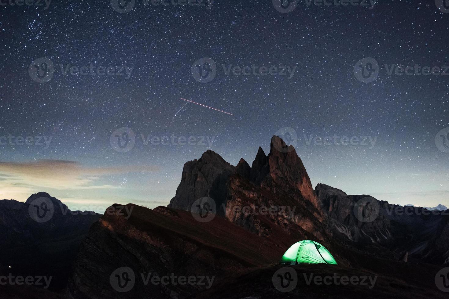 stelle cadenti al cielo blu. foto notturna delle dolomiti seceda. turisti che riposano nella tenda verde