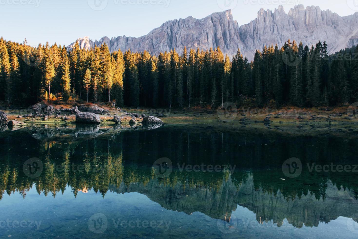 momento del tramonto. paesaggio autunnale con lago limpido, bosco di abeti e montagne maestose foto