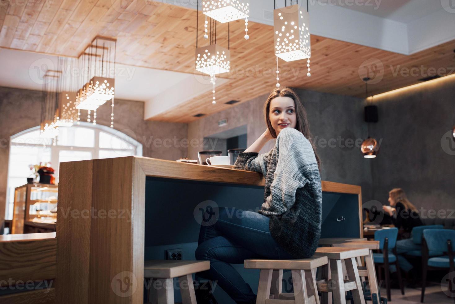 donna sorridente al bar utilizzando il telefono cellulare e messaggiando nei social network, seduta da sola foto