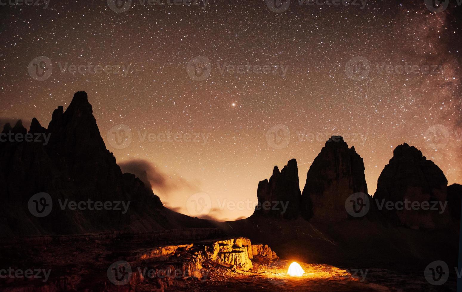 colline catturate di notte con stelle colorate e via lattea sullo sfondo. turisti in tenda. tre cime montagne con tre cime foto