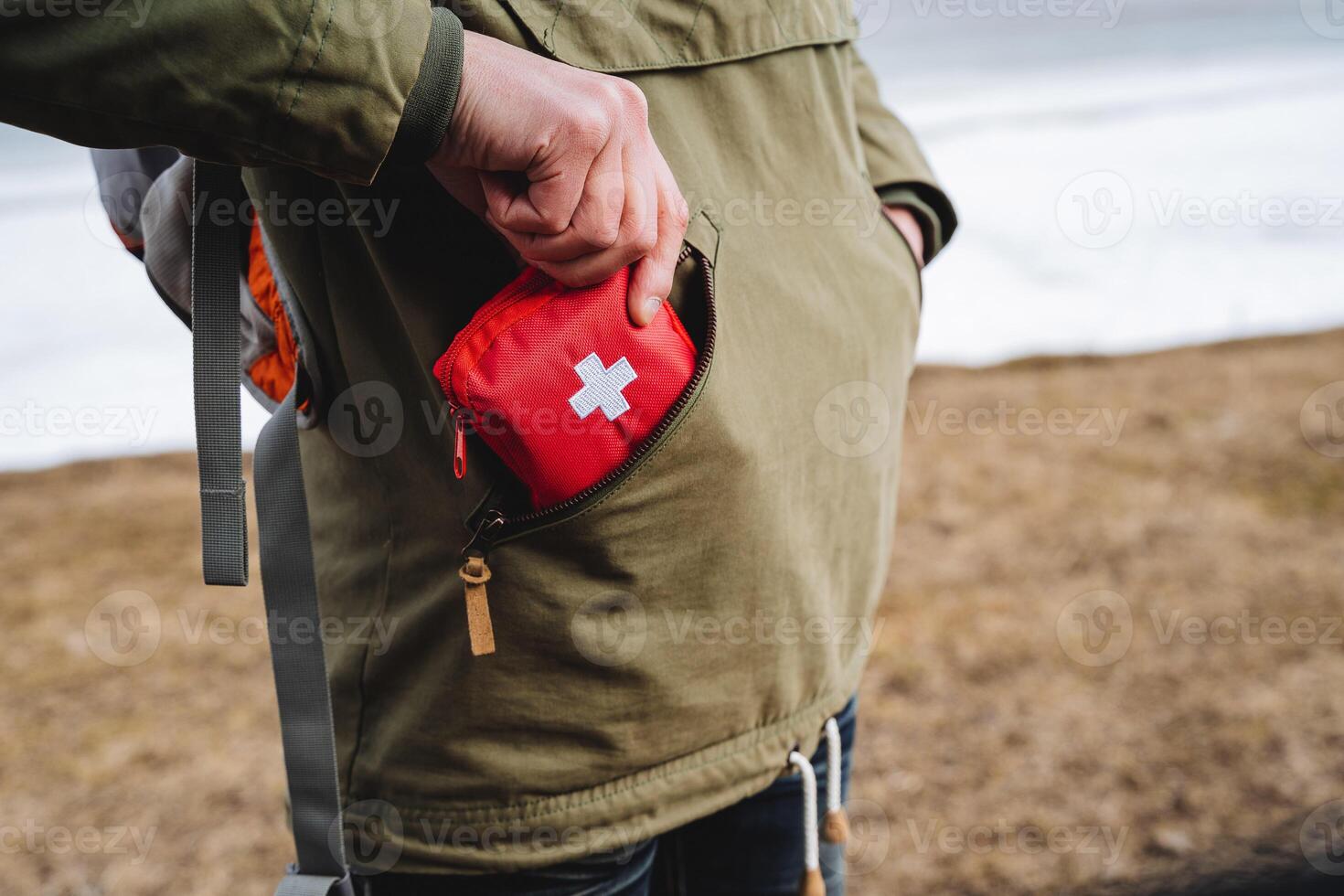 un' turista persona mette nel il suo tasca un' primo soccorso kit per un' escursione, mobile medico cura per un lesione, un' rosso scatola con compresse, un ambulanza kit. foto