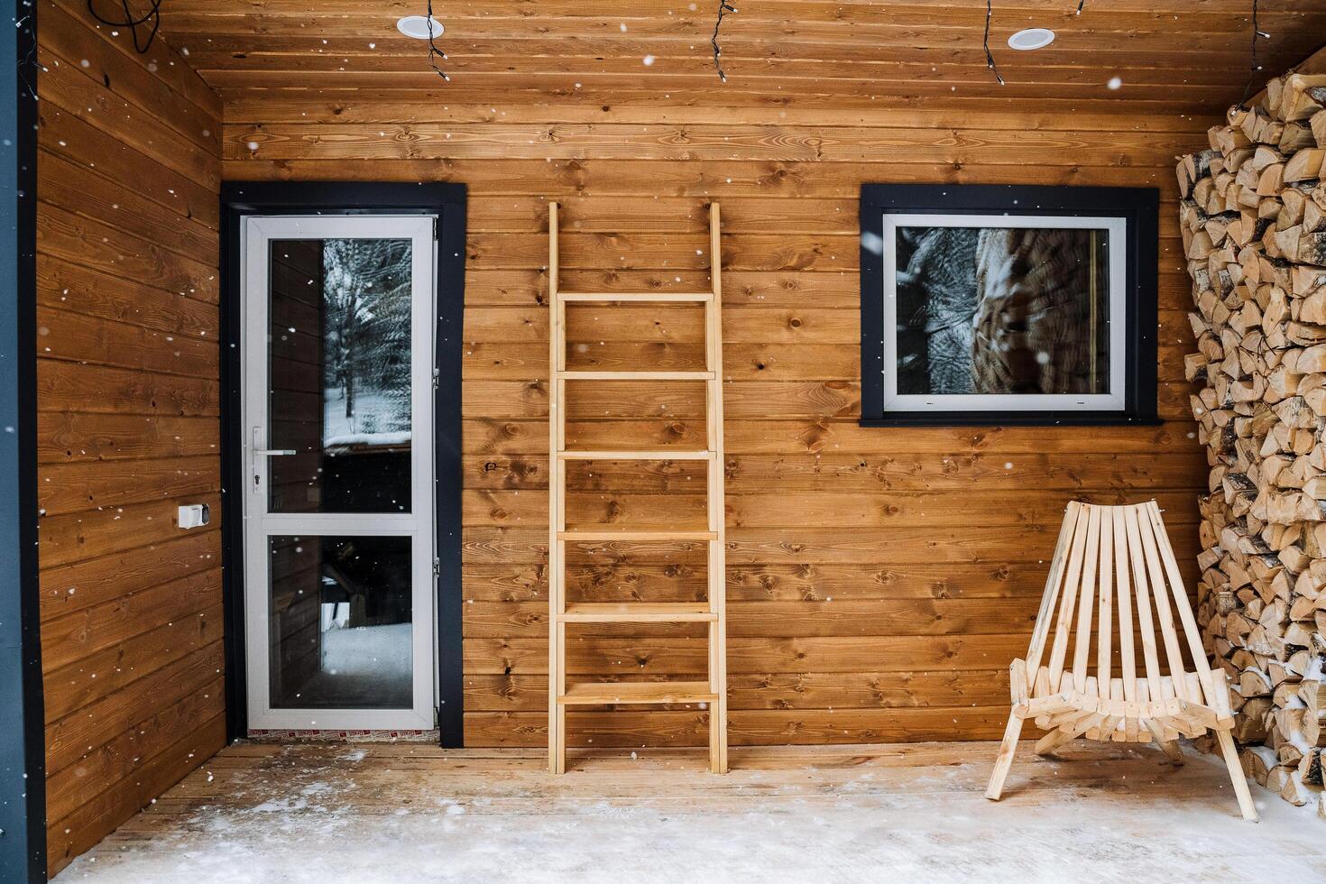 giardino carrozza longue per all'aperto posti a sedere fatto di Di legno. registri. tritato betulla legna da ardere nel un' tronco d'albero. di legno scala contro il parete. componibile Casa con plastica finestre foto