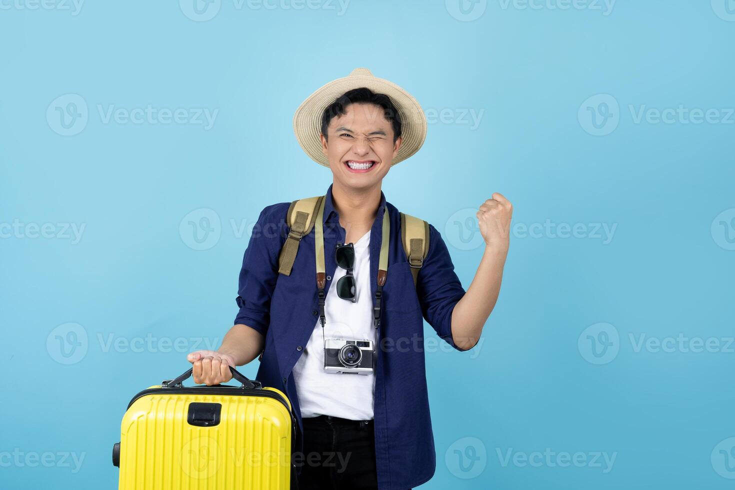 contento asiatico viaggiatore turista uomo Tenere valigia isolato su blu sfondo. foto