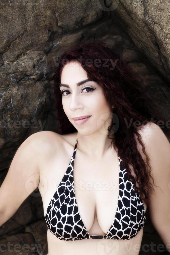 attraente latina donna bikini superiore seduta tra rocce all'aperto foto