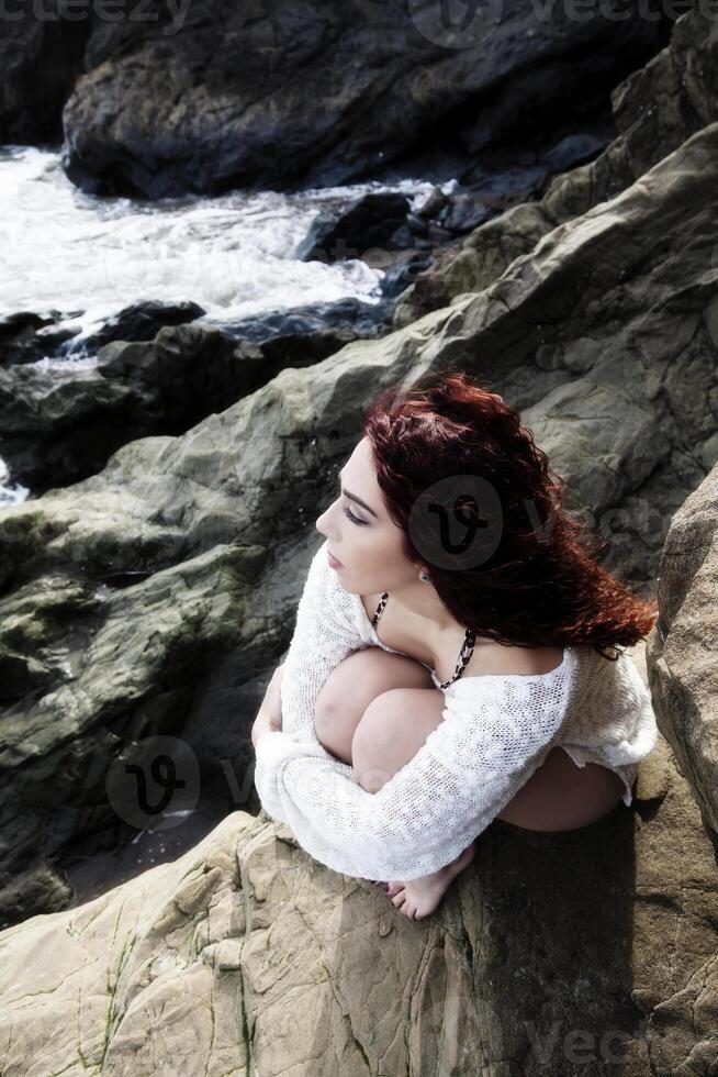 latina donna seduta su rocce a mare riva guardare su foto