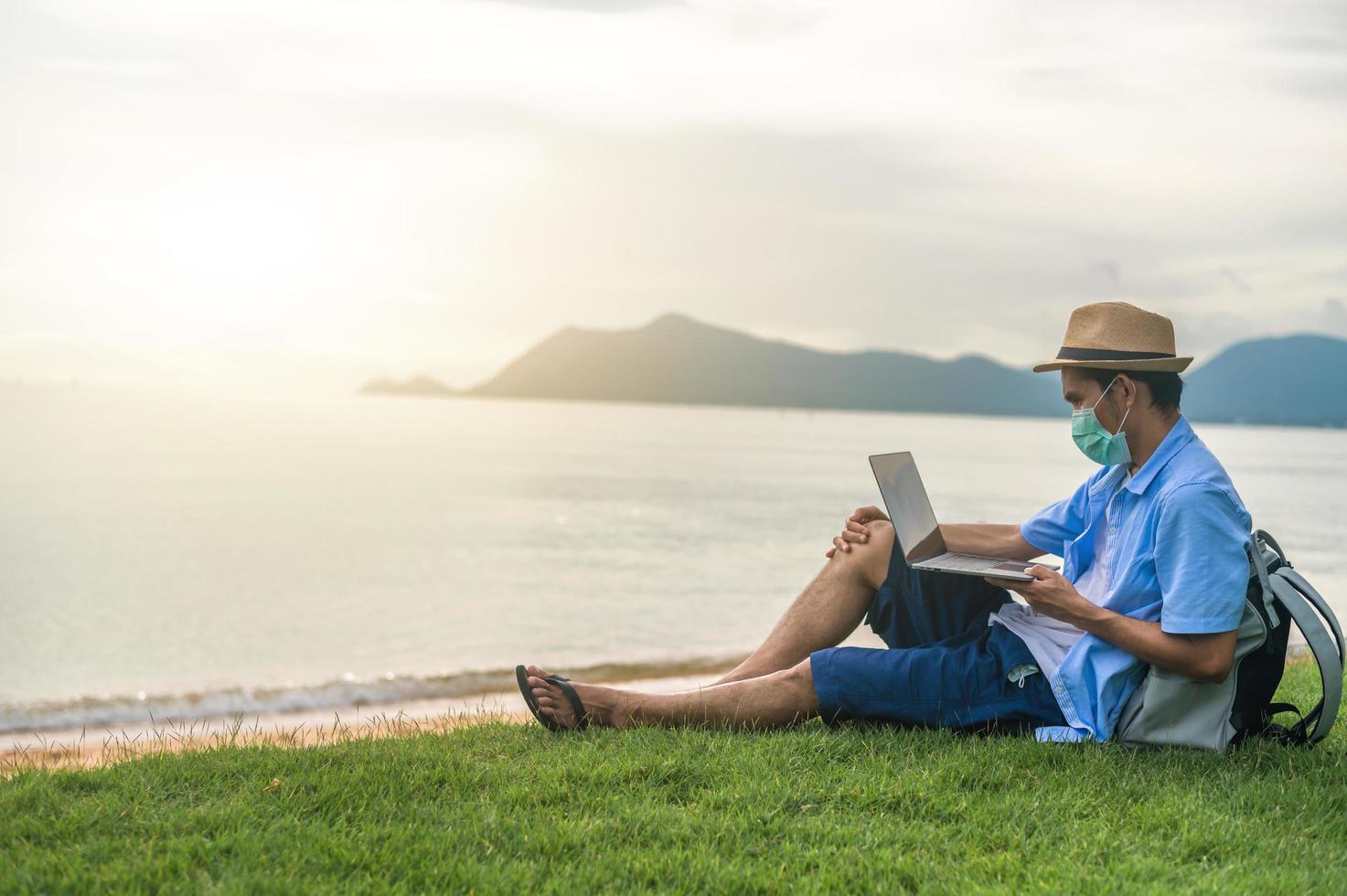 l'uomo indossa la maschera utilizzando il computer portatile sulla spiaggia mare e uomo viaggio vacanza phuket sandbox thailandia sono libertà vita finanziaria foto