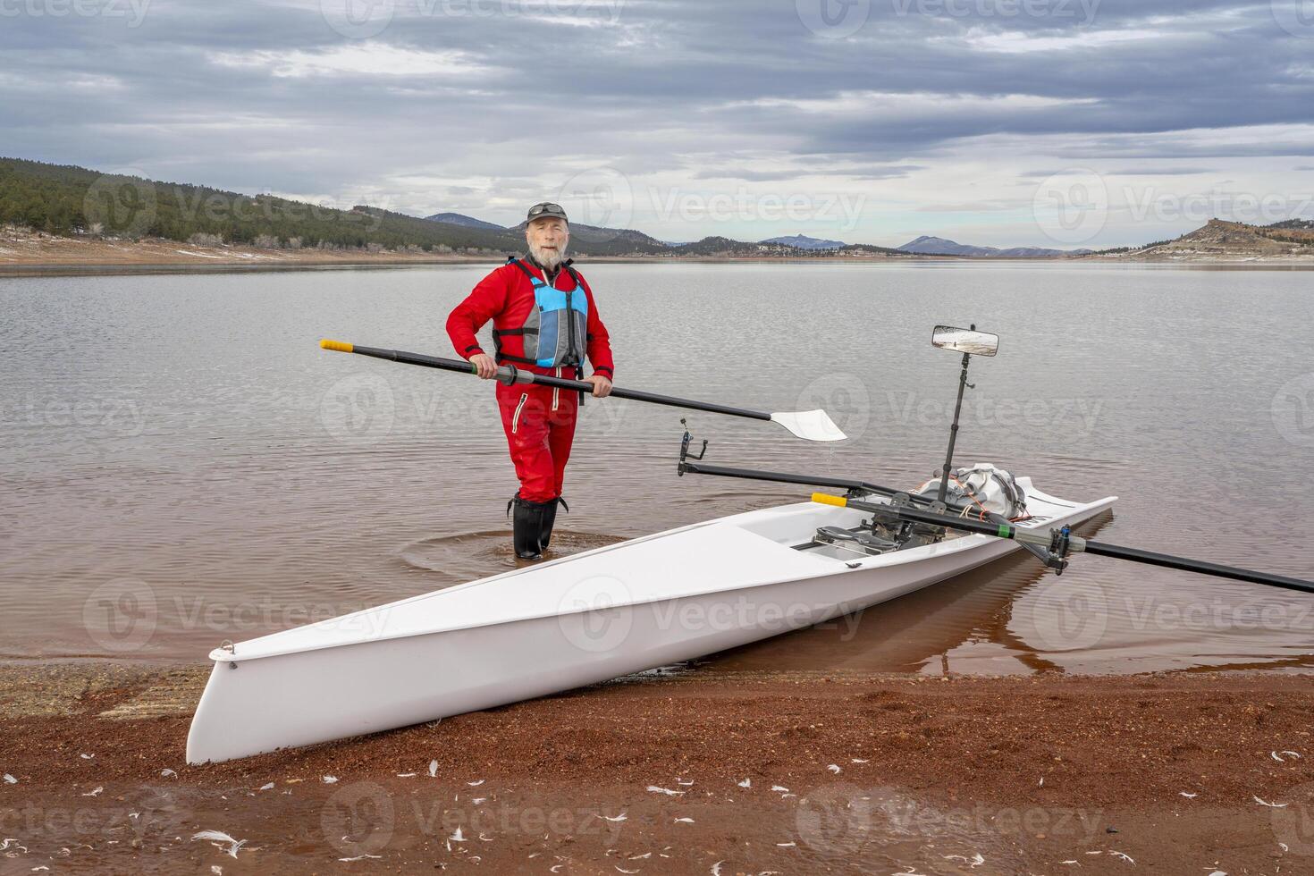 anziano vogatore è sartiame il suo canottaggio conchiglia su un' riva di carrettiere lago nel settentrionale Colorado nel inverno scenario foto