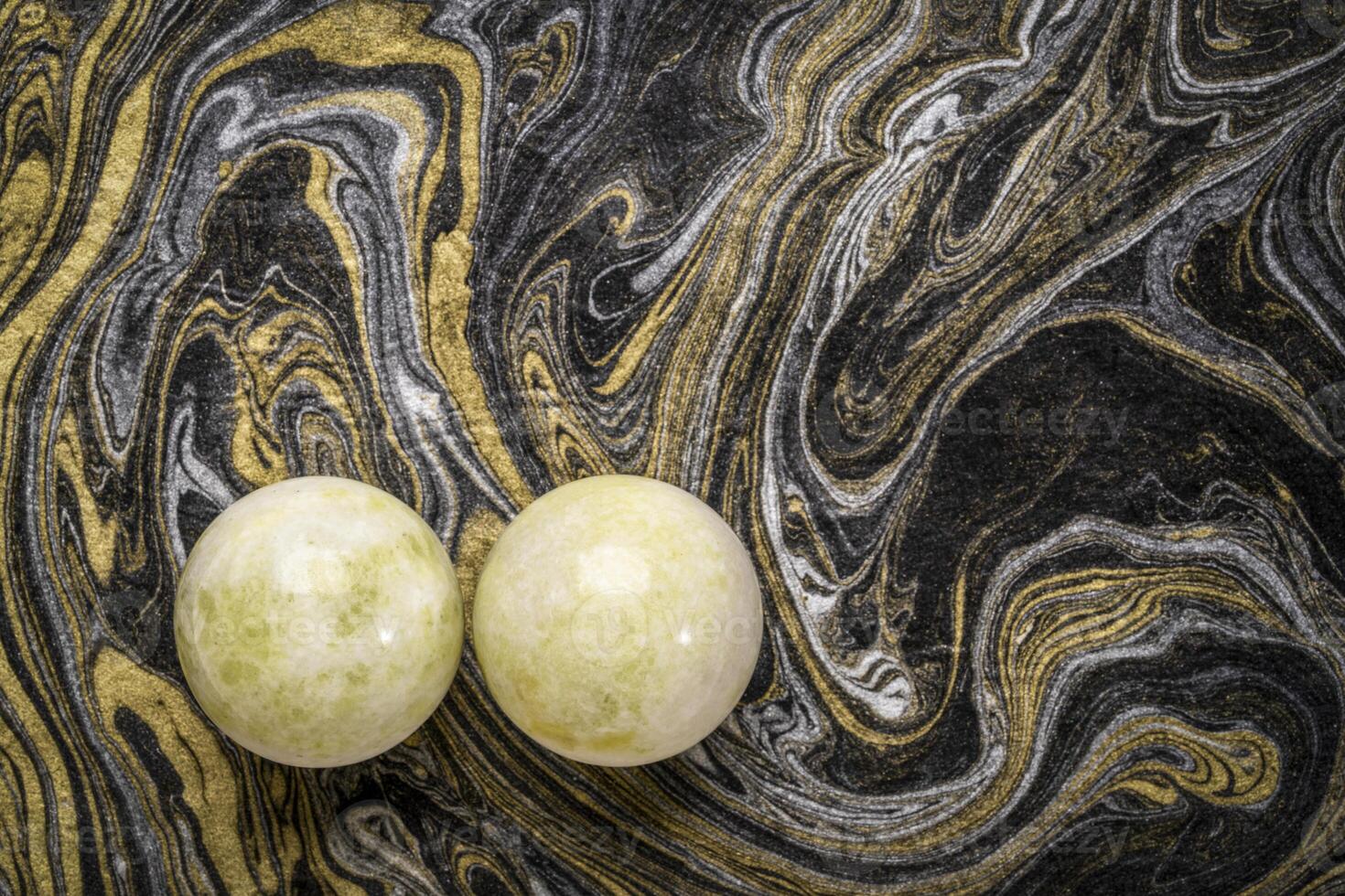 un' paio di verde marmo Cinese medicina palle contro nero e d'oro marmorizzato carta foto