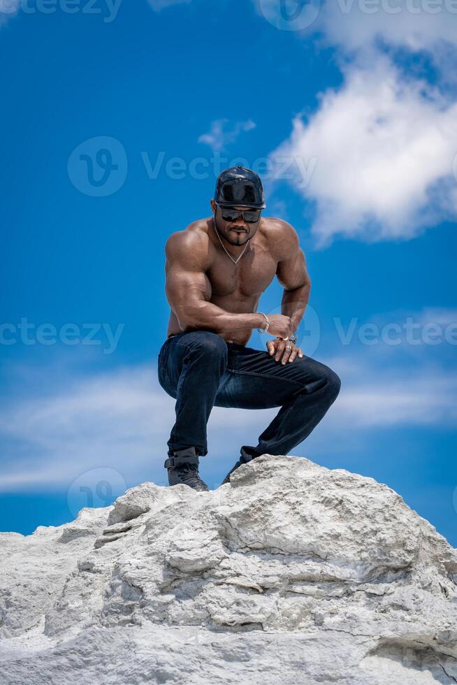 forte elegante uomo a piedi su chiaro blu cielo sfondo. A petto nudo bodybuilder mostrando il suo muscoli. foto