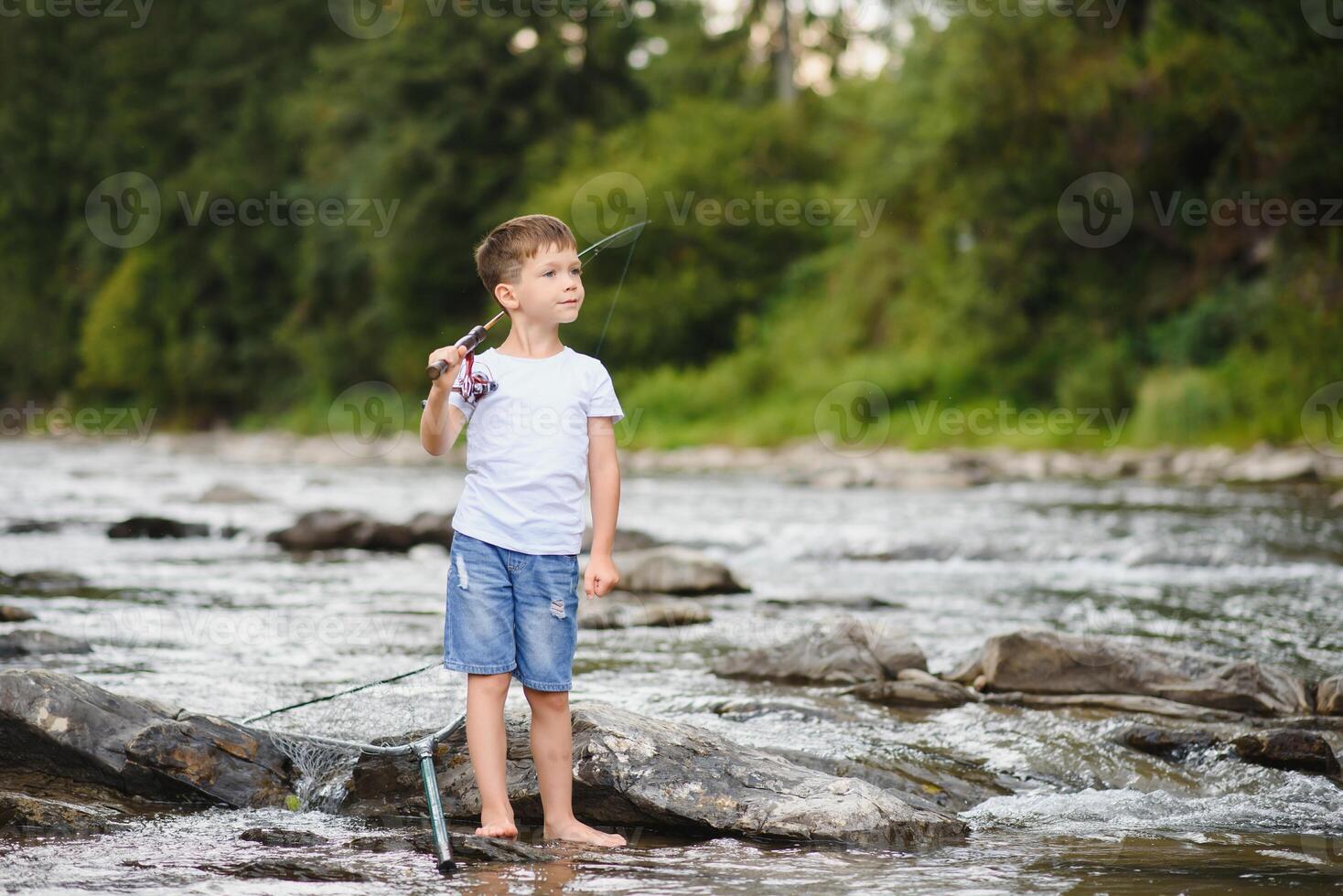 carino ragazzo nel bianca t camicia pesca nel il fiume e ha divertimento, sorrisi. vacanza con bambini, vacanze, attivo fine settimana concetto foto