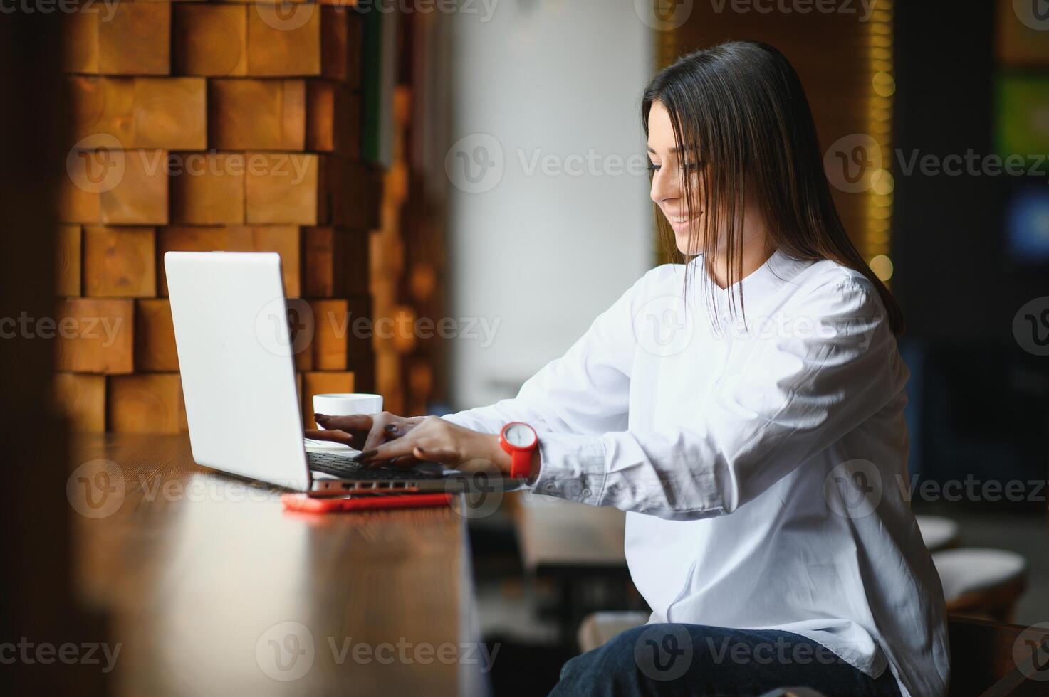 giovane donna riuscito manager è parlando attraverso mobile Telefono con possibile finanziario azienda dipendente e lettura loro curriculum vitae su portatile il computer portatile computer durante a distanza colloquio nel co-working spazio foto