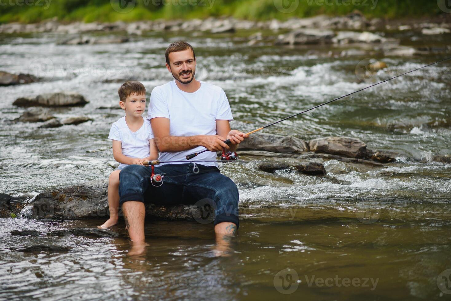 un' padre insegnamento il suo figlio Come per pesce su un' fiume al di fuori nel estate luce del sole foto