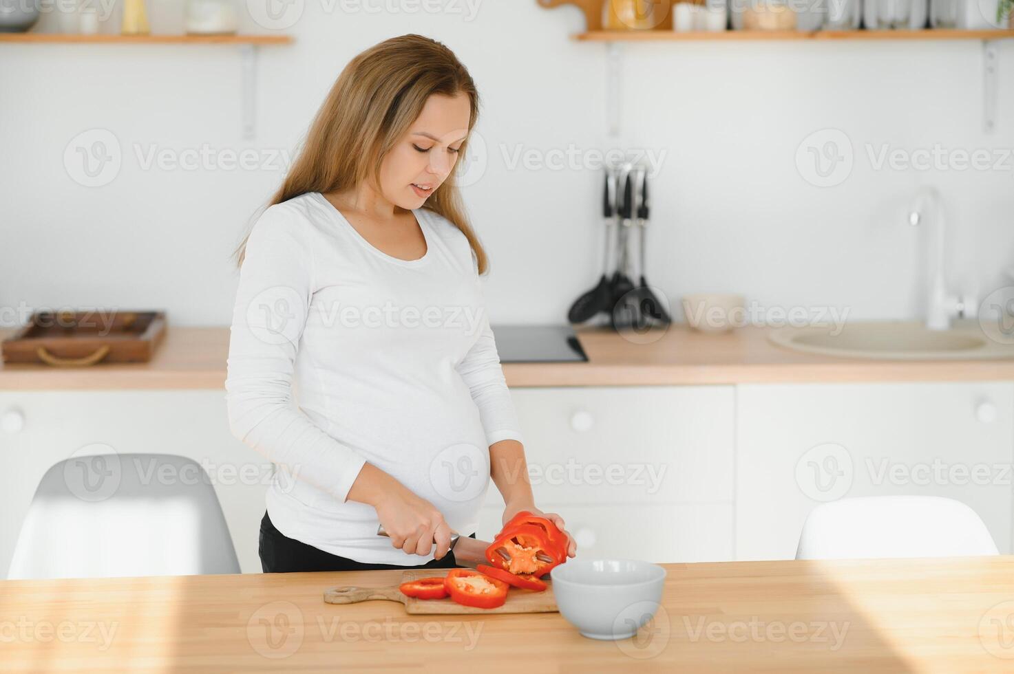 gravidanza, cucinando cibo, salutare stile di vita, persone e aspettativa concetto - contento incinta donna con coltello chopping cetriolo e preparazione verdura insalata a casa foto