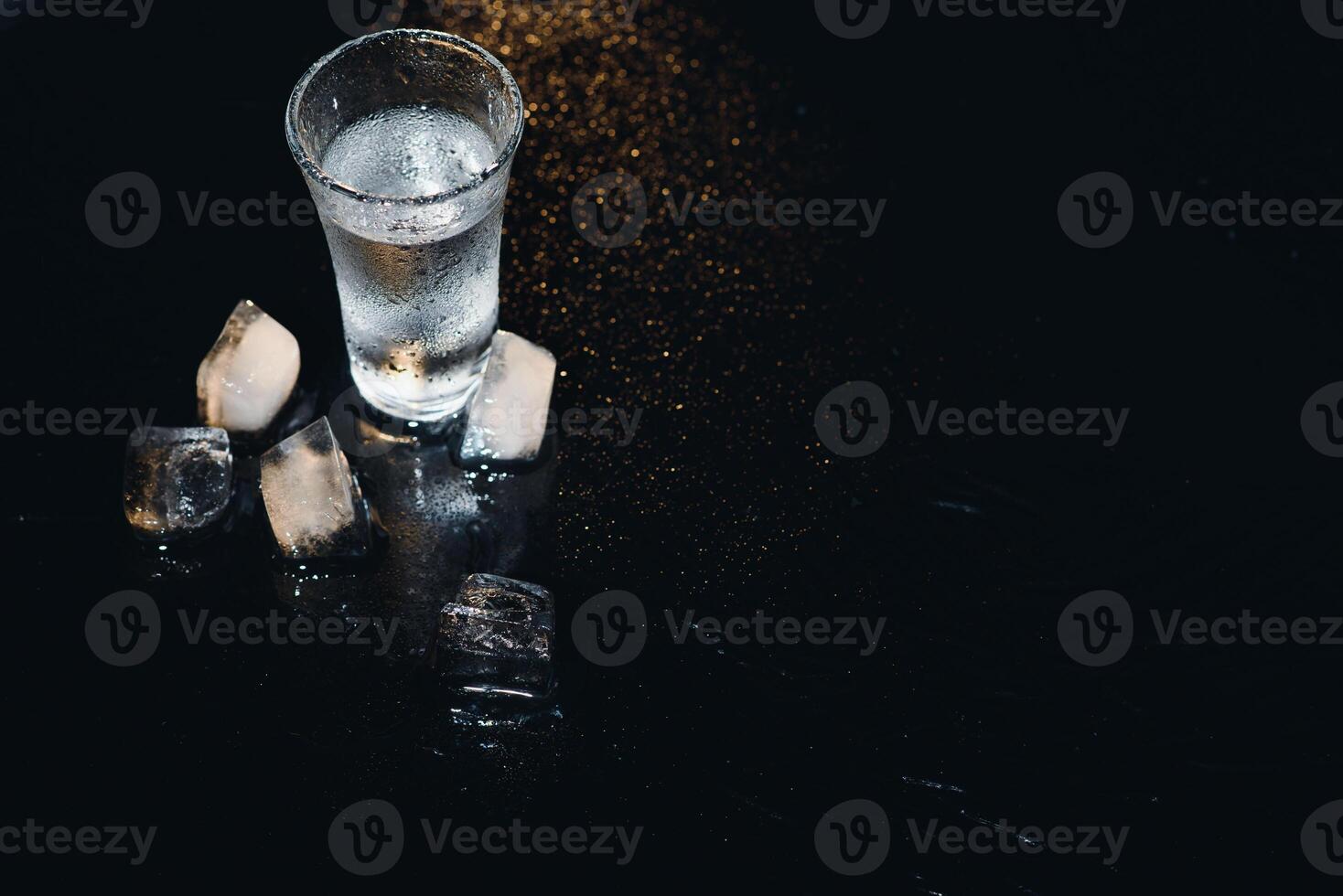 Vodka tiro con ghiaccio su nero tavolo, copia spazio. foto