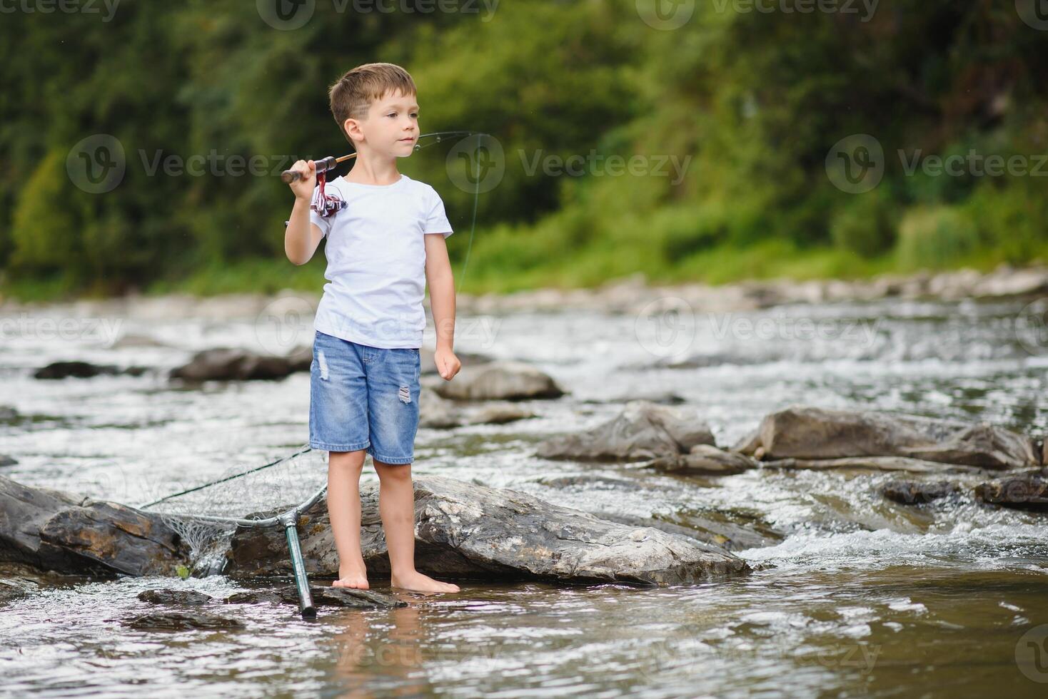 carino ragazzo nel bianca t camicia pesca nel il fiume e ha divertimento, sorrisi. vacanza con bambini, vacanze, attivo fine settimana concetto foto