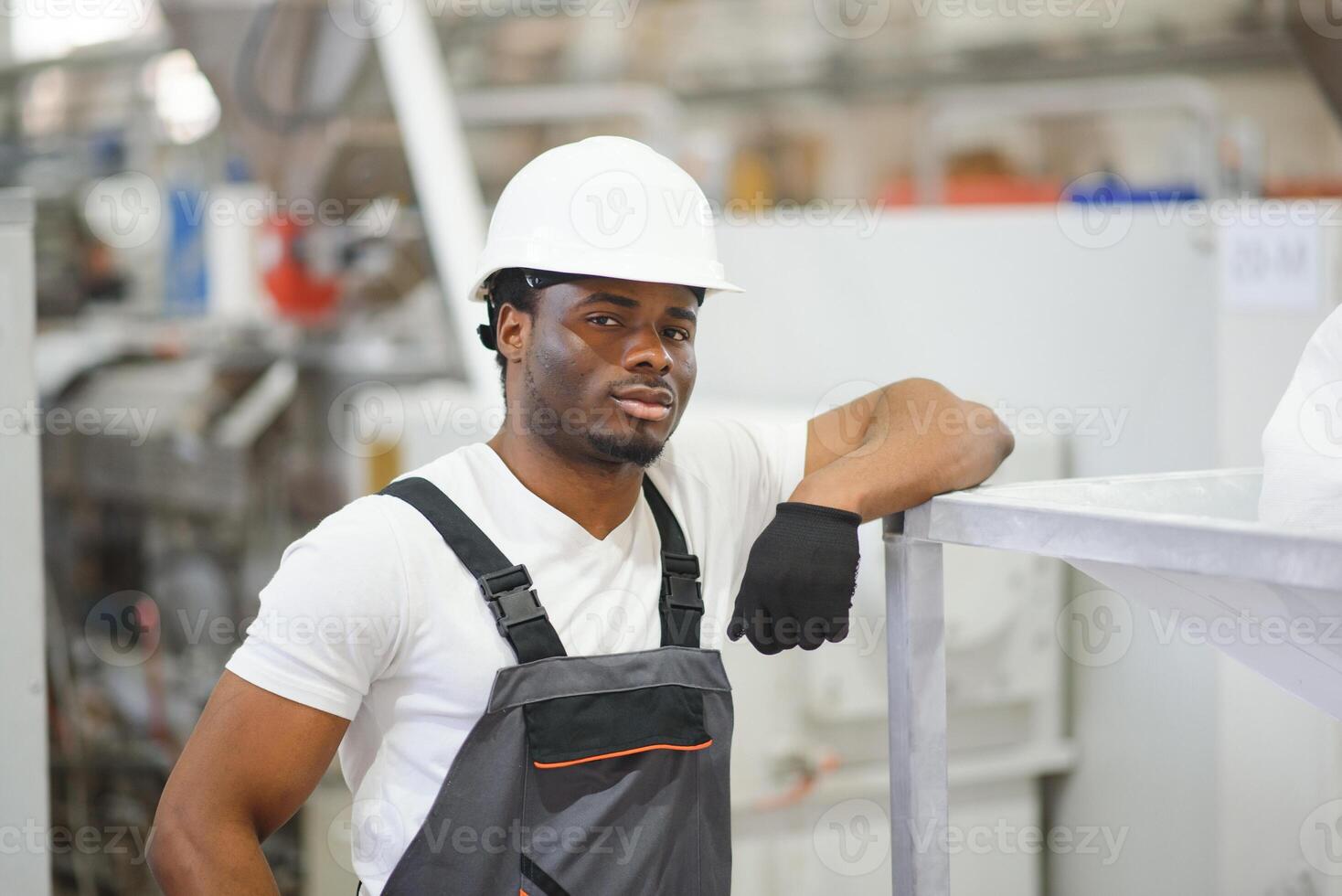 ritratto di industriale ingegnere. sorridente fabbrica lavoratore con difficile cappello in piedi nel fabbrica produzione linea foto