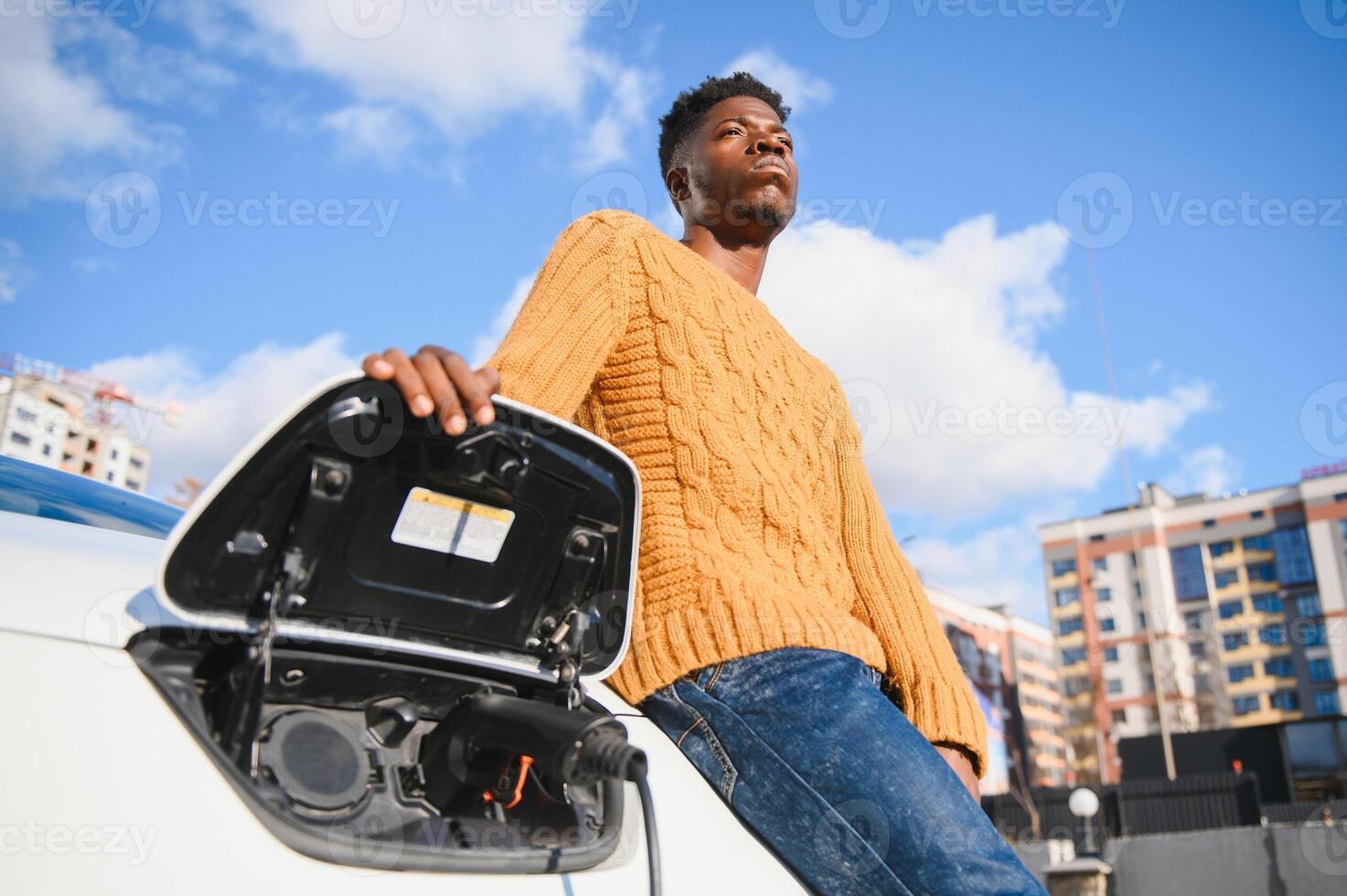 elettrico macchine, ev concetto, eco amichevole carburante. ritratto di giovane sorridente nero uomo, ricarica il suo moderno lusso elettrico auto foto