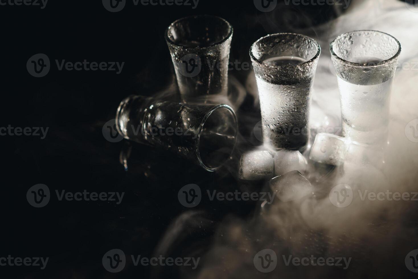 avvicinamento Visualizza di bottiglia e bicchieri di Vodka in piedi isolato su nero. foto