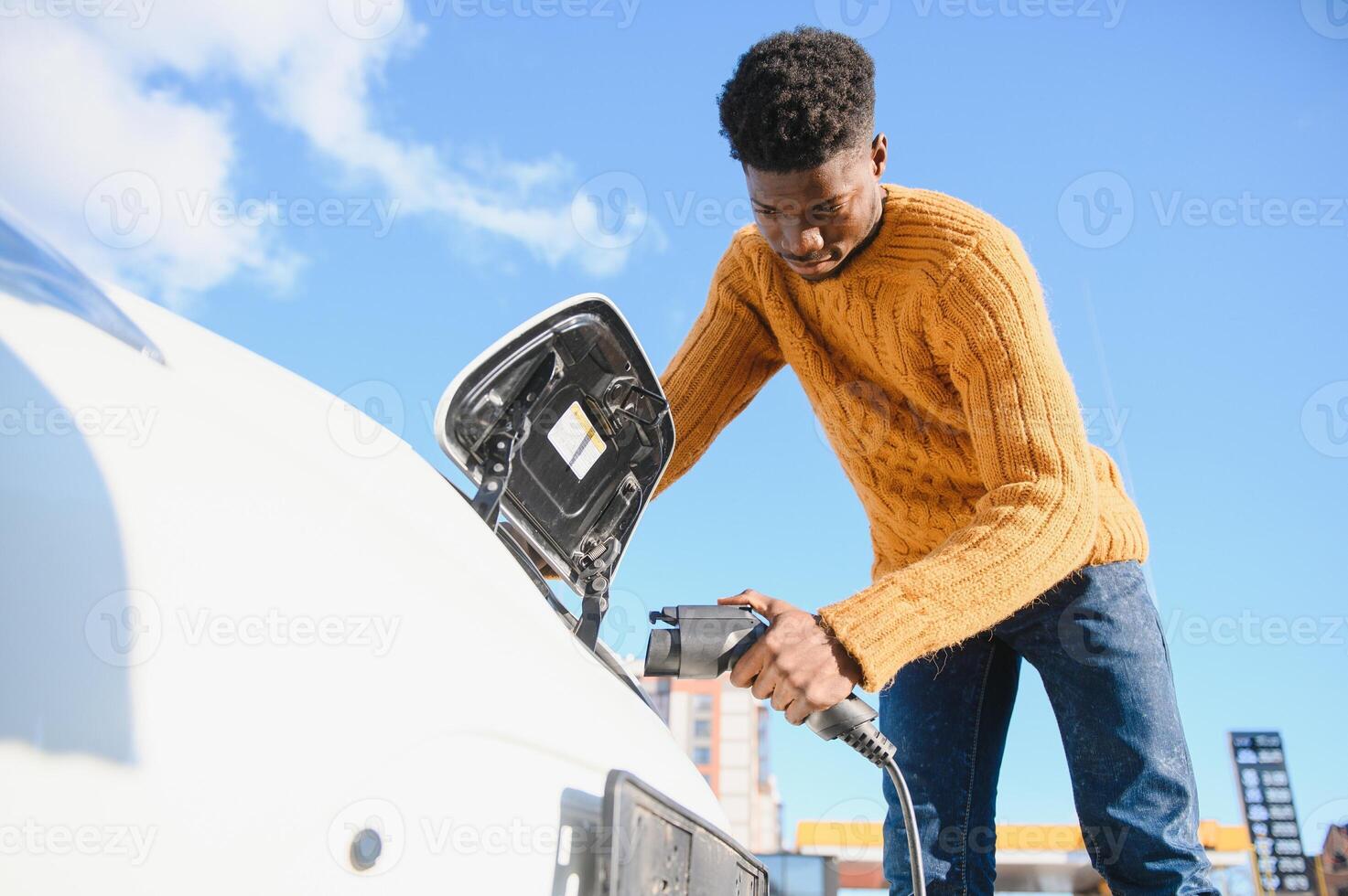 africano americano uomo ricarica il suo elettrico macchina. foto