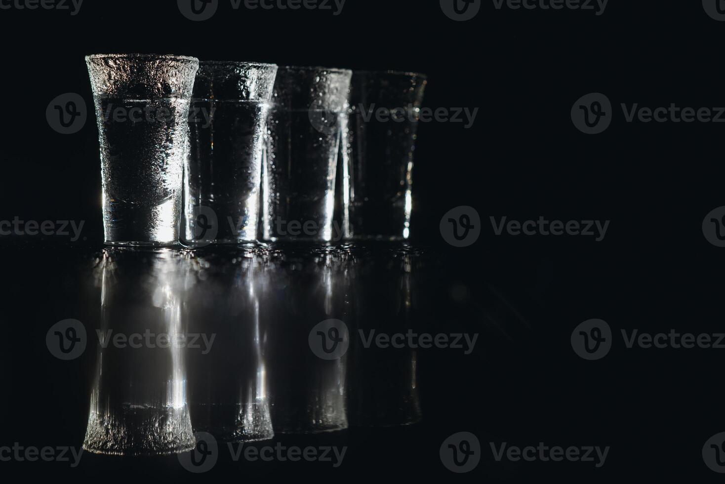Vodka scatti con ghiaccio su nero tavolo, copia spazio. foto